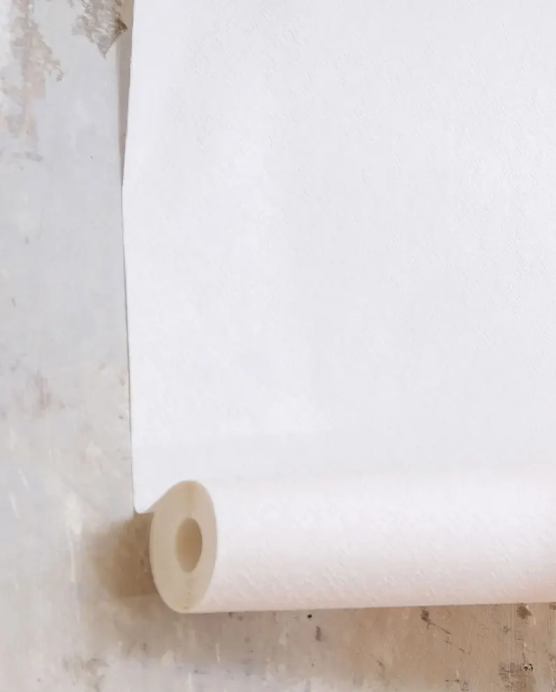Rouleau de papier peint déroulé contre un mur