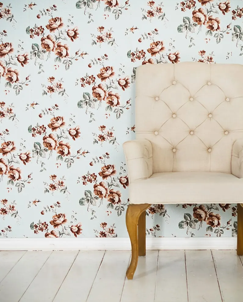 Fauteuil capitonné devant un papier peint fleuri